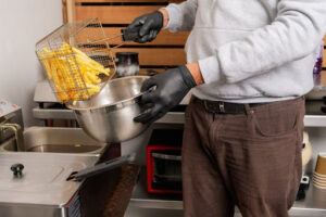 A man pouring french fries into a bowl.