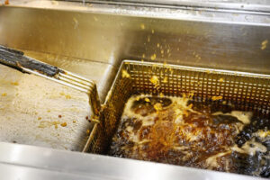 Greasy deep fryer with splashing boiling oil.
